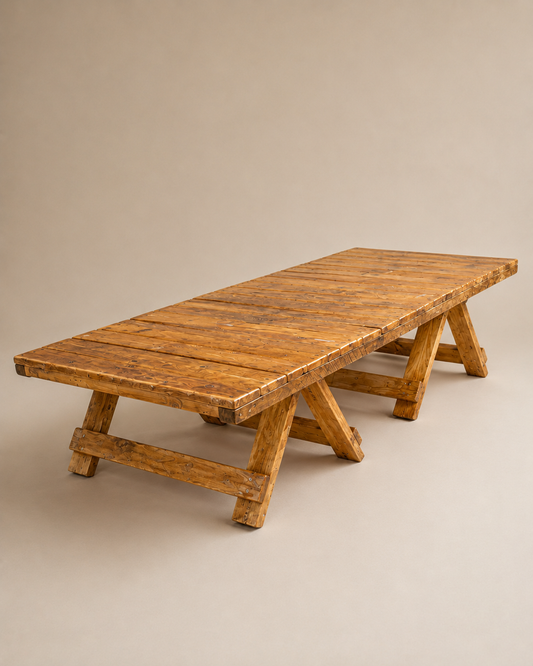 A rustic rectangular wooden table with a slatted top and A-frame legs, photographed on a plain warm beige studio background.
