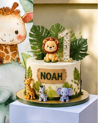 A decorated round birthday cake with safari-themed animal figurines and green leaves. The front of the cake has a wooden-style sign reading NOAH, and the top features a lion figurine beside a large number 1 topper.