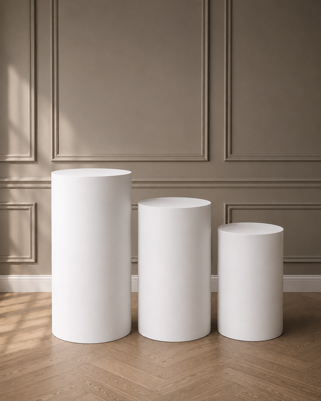 Three white cylindrical objects on a wooden floor with a paneled wall background